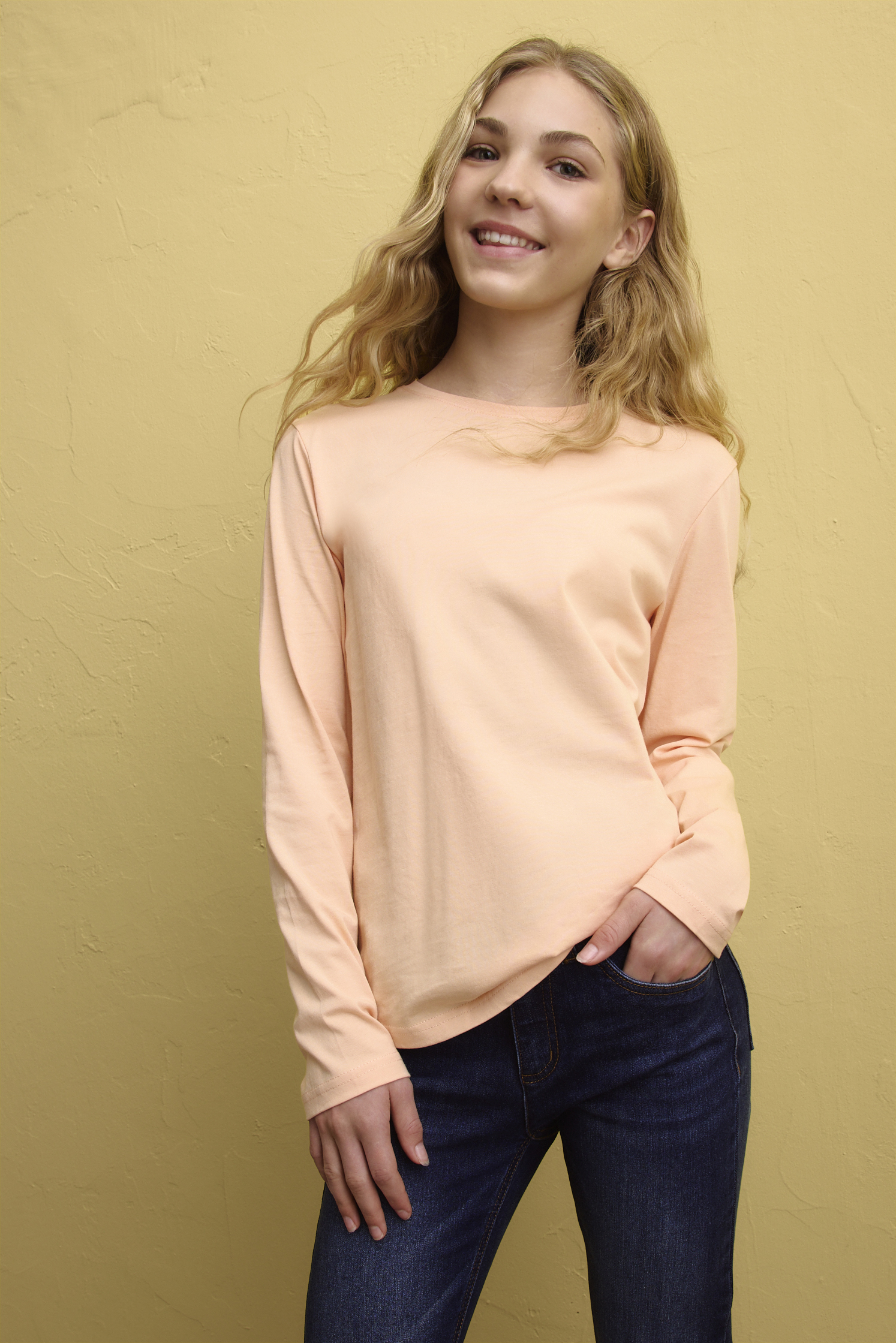 Zartes Pfirsichfarben trifft auf dunkles Denim: Lässiger Look mit Pullover und Jeans.