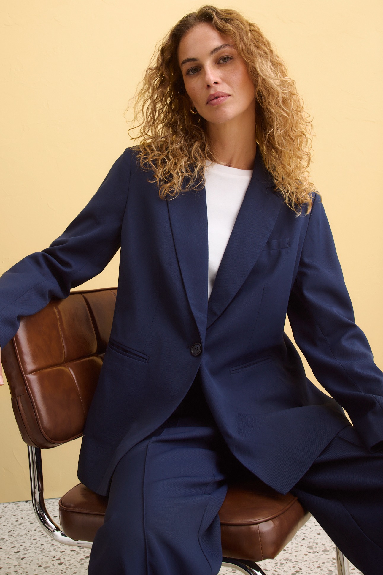 Eleganter dunkelblauer Hosenanzug mit weißem Oberteil. Klassischer Blazer und weite Hose für einen stilvollen Look.